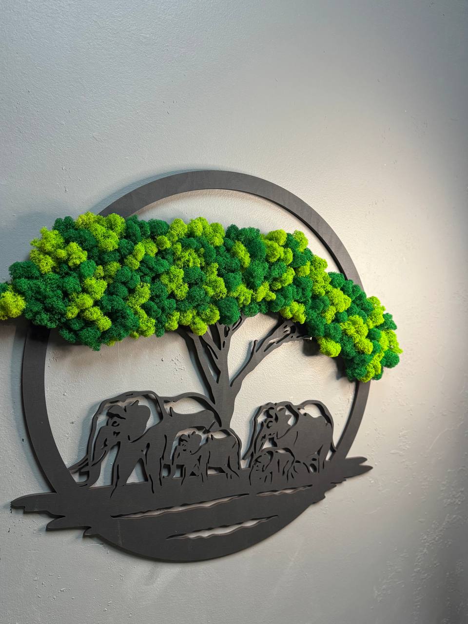 Decorative wall art with green tree and black animal silhouettes on a gray background