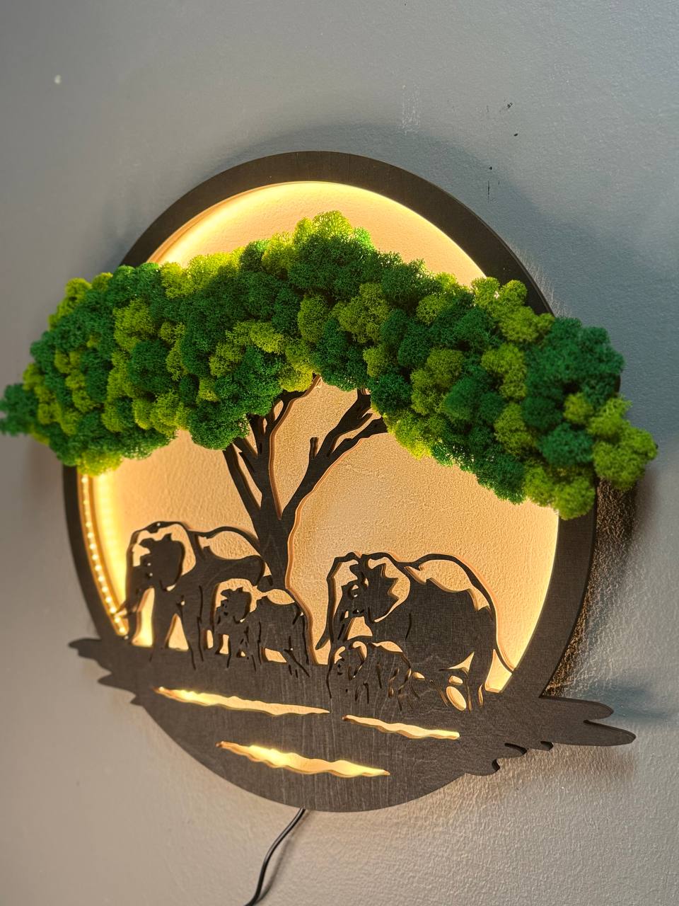Decorative wall art with silhouettes of animals under a tree, illuminated from behind.